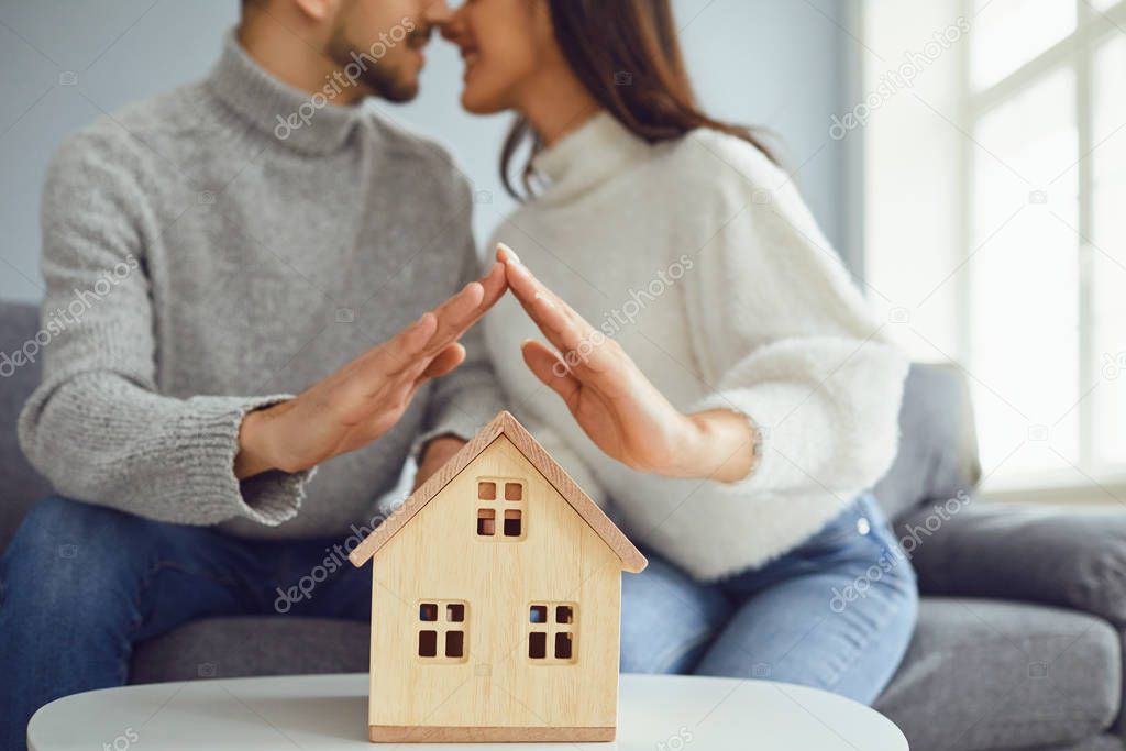Hands of family couple holding a model of a house