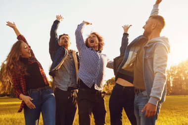 Neşeli arkadaşlar parkta ellerini kaldırdı .