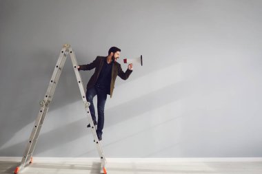 Merdivenlerde sakallı bir işadamı elinde bir megafonla gri bir arka planda bağırıyor..