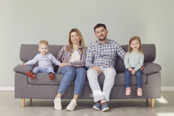 Gelukkig grappig gezin met kinderen glimlachend zittend op een bank — Stockfoto