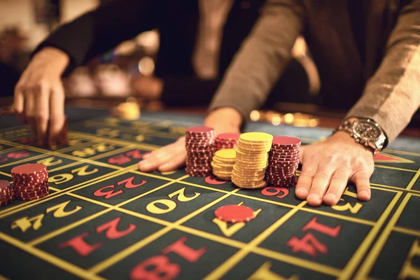 Primer plano de personas manos que ponen fichas en la mesa de ruleta en el casino . —  Fotos de Stock