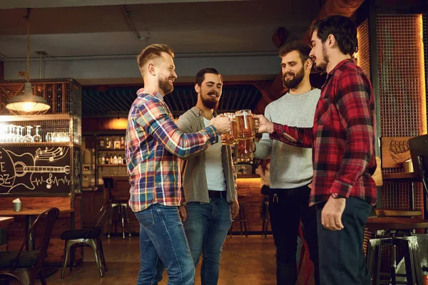 Grupo de amigos felizes batendo copos com cerveja em um bar de esportes . — Fotografia de Stock