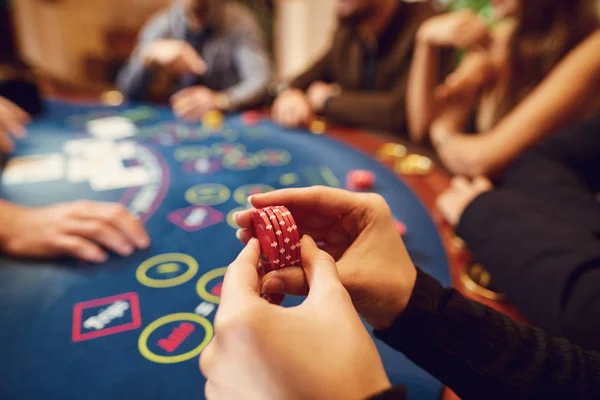 Chips in een gokspeler hand aan een tafel in een casino. — Stockfoto