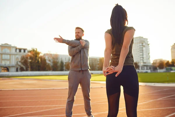 Couple in sportswear doing warm-up at the stadium — Stock Photo, Image