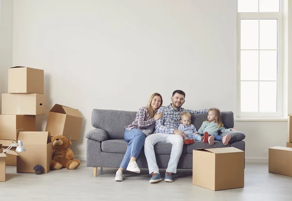 Familia feliz con niños moviéndose con cajas en una nueva casa de apartamentos . — Foto de Stock