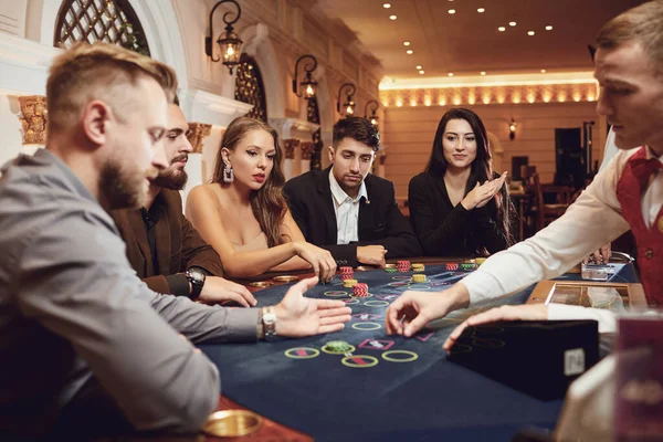 Eine Gruppe wohlhabender junger Leute zockt in einem Casino. — Stockfoto