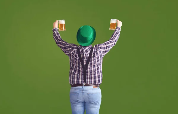 Happy St. Patricks Day. Back view a fat man in a green hat holds his hands up glasses with beer — 스톡 사진