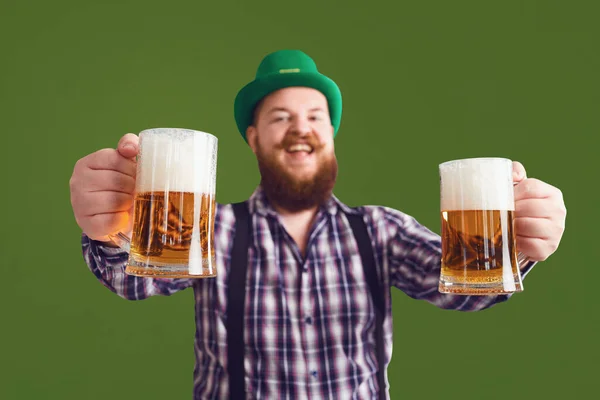 Happy St. Patricks Day. Fat man in a green hat holds his hands up glasses with beer — Stock Photo, Image