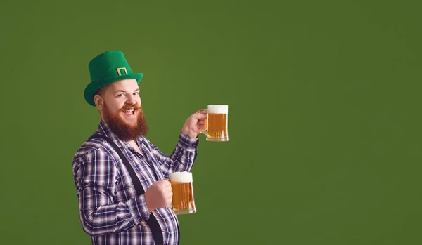 Happy St. Patricks Day. Fat man in a green hat holds his hands up glasses with beer — ストック写真