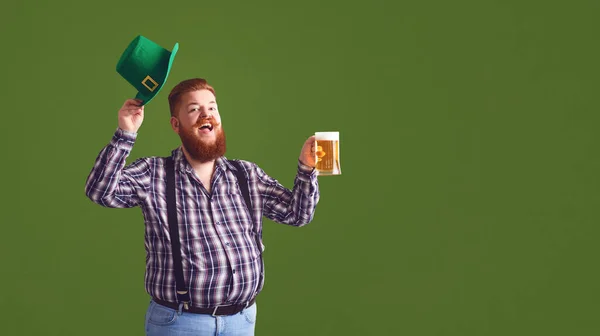 Feliz dia de St. Patricks. Gordo em um chapéu verde mantém as mãos erguidas óculos com cerveja — Fotografia de Stock