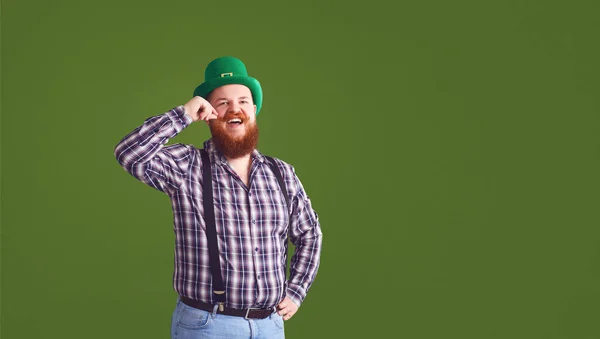 Feliz dia de St. Patricks. Gordo em um chapéu verde mantém as mãos erguidas óculos com cerveja — Fotografia de Stock