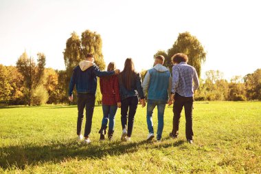 Young people walk through the meadow park in spring.