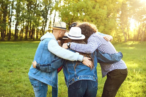 Een groep vrienden staat omarmen een picknick in het park. — Stockfoto