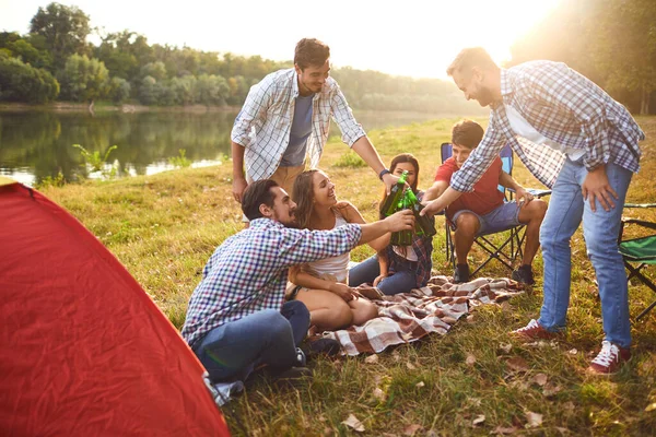 Молодые люди пьют, едят и звонят в стаканы на пикнике — стоковое фото