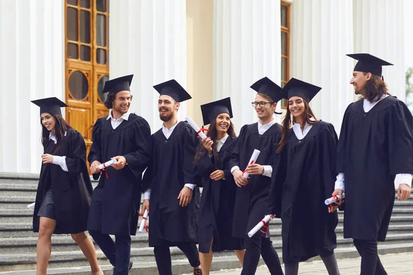 Skupiny absolventů studentů jdou na univerzitu. — Stock fotografie