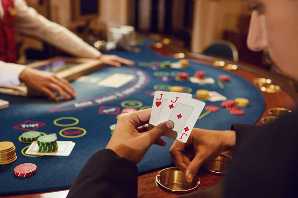 Mãos fechadas de um jogador de poker verificando cartas em um cassino . — Fotografia de Stock