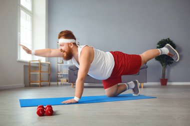 Funny fat man doing yoga exercises in the room.