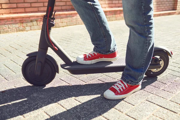 Pernas de um homem em uma scooter elétrica em uma rua da cidade . — Fotografia de Stock