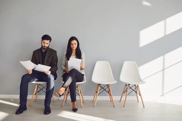 Entrevistadores masculinos y femeninos con papeles en sillas — Foto de Stock