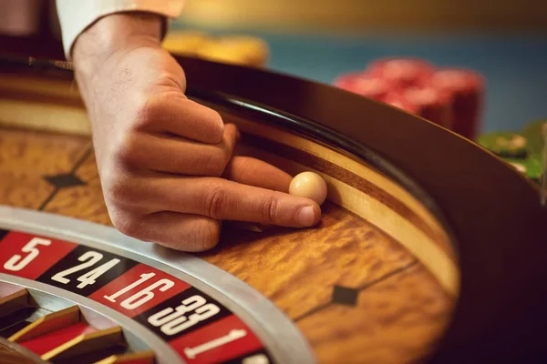 Hand av en croupier med en boll på ett roulettehjul under ett spel i ett kasino. — Stockfoto