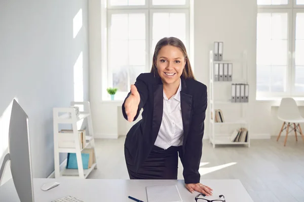 Handshake offering.Smiling female businessman makes a handshake offering at a table in the office.