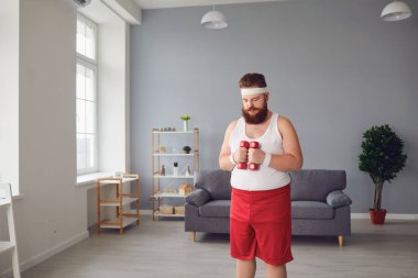 Elinde dambıllar olan komik şişman adam odada egzersiz yapıyor..