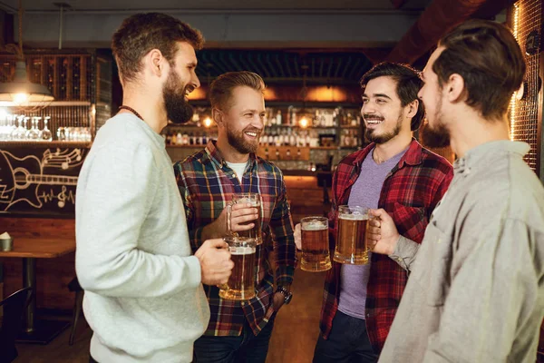 Groep gelukkige vrienden klinkende glazen met bier in een sportbar. — Stockfoto