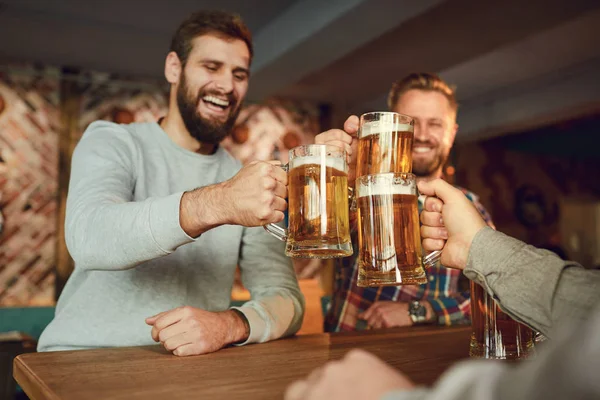 Group of happy friends clinking glasses with beer at a sports bar. — 스톡 사진