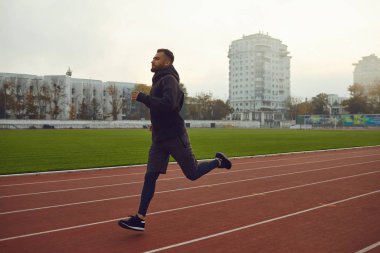 Genç bir atlet siste bir stadyumda koşuyor..