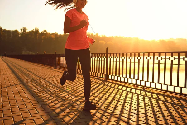 Runner runs on the road in the sun at sunset in an autumn park. — Stock Photo, Image