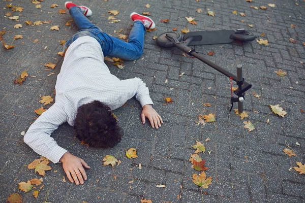 Accident avec un scooter électrique. Un homme est tombé d'un scooter dans une rue de la ville . — Photo