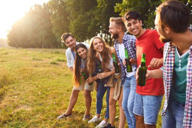 Young people drink and clink glasses at a picnic