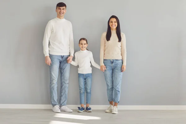 Gelukkig familie glimlachen terwijl staan tegen grijs achtergrond. — Stockfoto