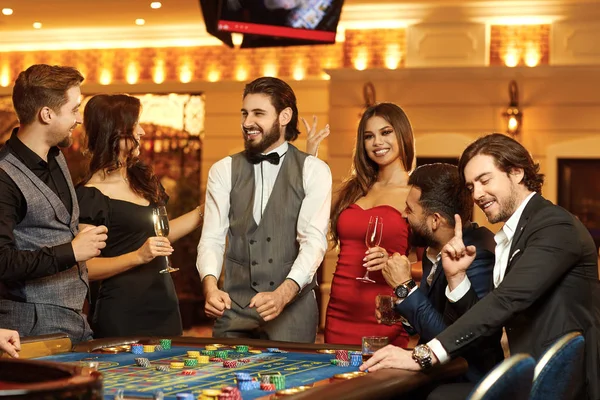 グループの幸せな人々はカジノのルーレットテーブルで賭けギャンブルをします. — ストック写真