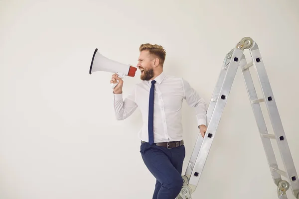 Un hombre de negocios barbudo en las escaleras con un megáfono en la mano grita — Foto de Stock