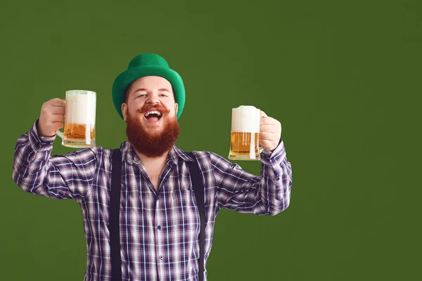 Happy St. Patricks Day. Fat man in a green hat holds his hands up glasses with beer — ストック写真