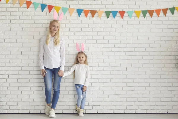Happy easter. Mother and daughter with rabbit ears smiling against a white brick wall. — Φωτογραφία Αρχείου