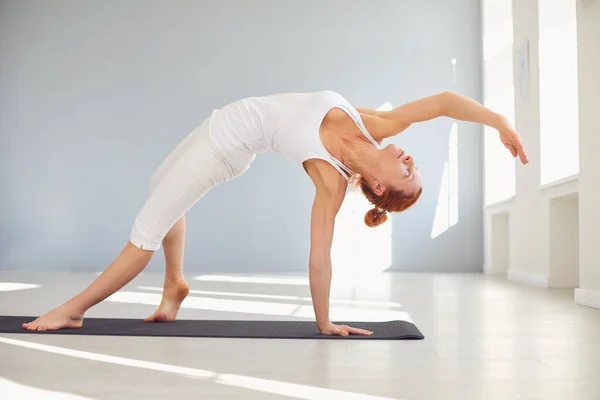 Yoga girl. Fitness girl in white clothes is enjoying yoga doing exercises in a white room Royalty Free Stock Images