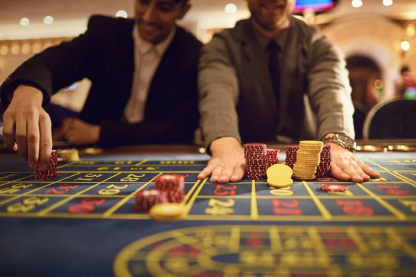 Közelkép az emberek kezét szóló zseton rulett asztal a kaszinóban. — Stock Fotó