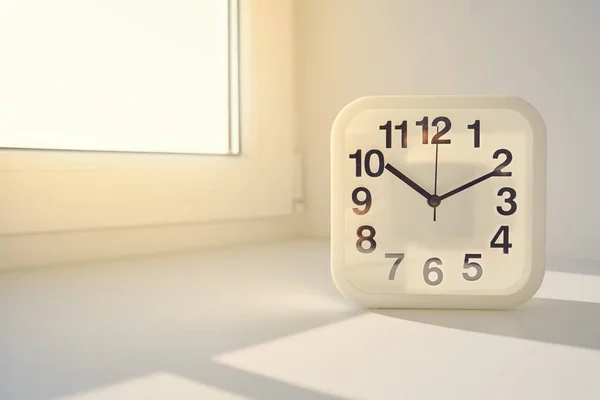 Rectangular white alarm clock on sunny window background. — Stok fotoğraf