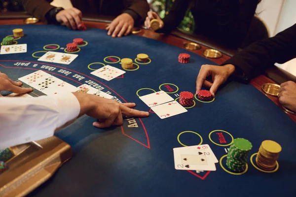 Croupier segura cartas de poker em suas mãos em uma mesa em um cassino . — Fotografia de Stock
