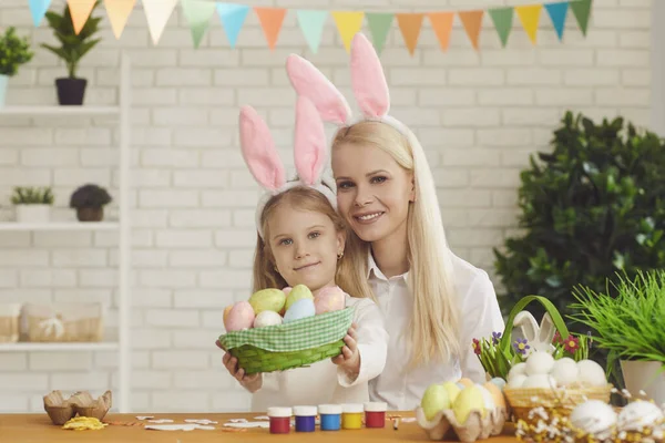 Joyeuse Pâques. Fille et mère aux oreilles de lapin décorent les œufs de Pâques assis à une table — Photo