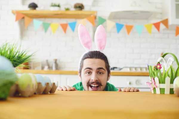 Happy Easter. A funny bearded man with rabbit ears smiling in a decorated room. — Stockfoto