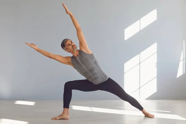 Yogacı. Bir adam gri bir odada yoga dengesi kuruyor.. — Stok fotoğraf