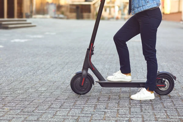 Jeune homme dans un casque monte un scooter électrique sur une rue de la ville en été — Photo