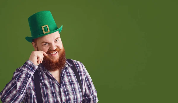 Feliz dia de St. Patricks. Gordo homem engraçado em um chapéu verde sorri em um fundo verde Dia das Patricks . — Fotografia de Stock