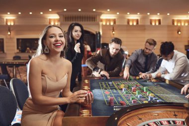 Happy smiling girl smiling at the roulette in a casino clipart