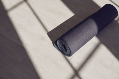 Parlak güneşli bir stüdyonun zemininde siyah yoga minderi..