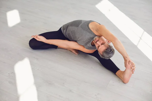 Hombre del yoga. Un hombre está practicando el equilibrio del yoga en una habitación gris. —  Fotos de Stock