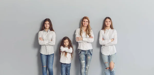 Glad leende mamma och döttrar står på en grå bakgrund. — Stockfoto